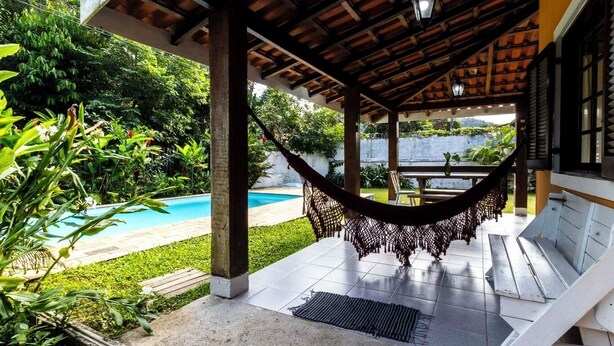 Un espace extérieur abrité comprenant un hamac, une piscine et une terrasse avec des sièges.