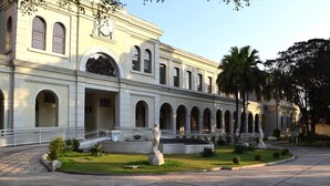 A classical building with a central courtyard, featuring a statue and palm trees. - Loft com smart lock e varanda no Bresser (São Paulo)