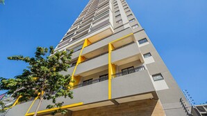 A high-rise building with multiple balconies and a clear blue sky. - Loft com smart lock e varanda no Bresser (São Paulo)