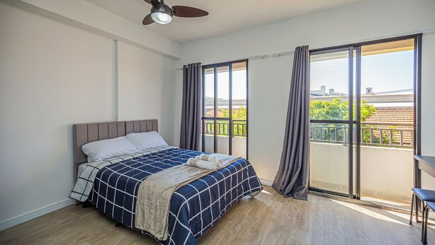 A bedroom with a bed, a ceiling fan, and a balcony with curtains. - Loft com smart lock e varanda no Bresser (São Paulo)