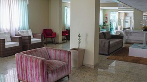 Amplia sala de estar con sofá a rayas, muebles de mimbre y una planta en maceta.