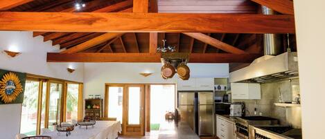 A spacious kitchen with high ceilings, wooden beams, and modern appliances.