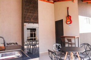 Eine Küche mit Gasherd, Spüle und Grill. Ein Tisch mit Stühlen und eine Gitarre an der Wand.