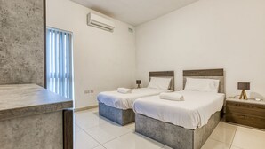 Ett modernt hotellrum med två sängar, en marmorskiva och ett fönster med persienner.