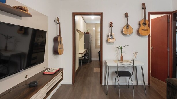Un salon avec un téléviseur, une guitare, une table à manger et une porte rouge.