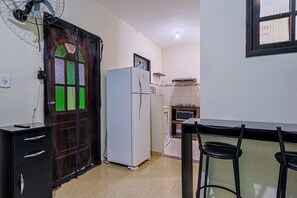 Une cuisine compacte équipée d’un réfrigérateur, d’un four à micro-ondes et d’un petit coin repas avec deux chaises.