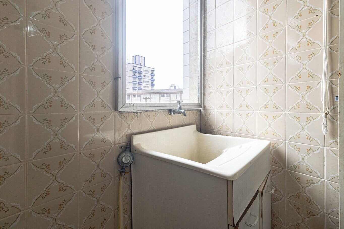 A bathroom with a sink, a window, and patterned tiles.