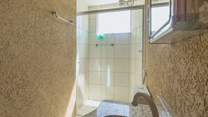 Un baño con ducha, lavamanos y toallero.