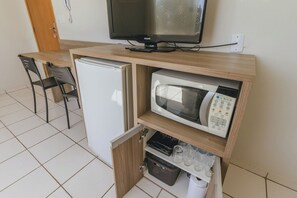 Eine kleine Küchenzeile mit Kühlschrank, Mikrowelle und einem Hängeschrank für Gläser.