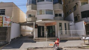 Un edificio de varios pisos con una entrada central y una motocicleta estacionada al frente.