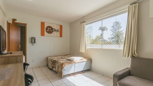 Una habitación pequeña y limpia con una cama, un escritorio, una silla y una ventana con cortinas.