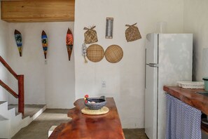 Eine Küche mit einer Holzausziehtheke, einem weißen Kühlschrank und verschiedenen gewebten Körben sowie dekorativen Gegenständen an der Wand.
