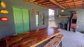 A rustic outdoor dining area with a wooden table and benches, a green door, and a brick oven. - Casa Brisa das Águas: Pool and BBQ (Tatuamunha)