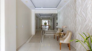Una hall d'hotel dal design moderno, con pavimento in marmo, una reception e un'area relax con sedie e un tavolino.