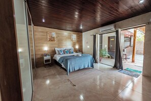 Ein Schlafzimmer mit Bett, Nachttischen und Blick nach draußen.