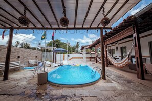 Ein Pool mit Pergola, umgeben von Liegestühlen und einer Hängematte.
