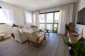 A modern living room with a sofa, armchairs, a coffee table, and a dining area. - Cobertura Duplex com piscina a 200m da Praia (Guarujá)