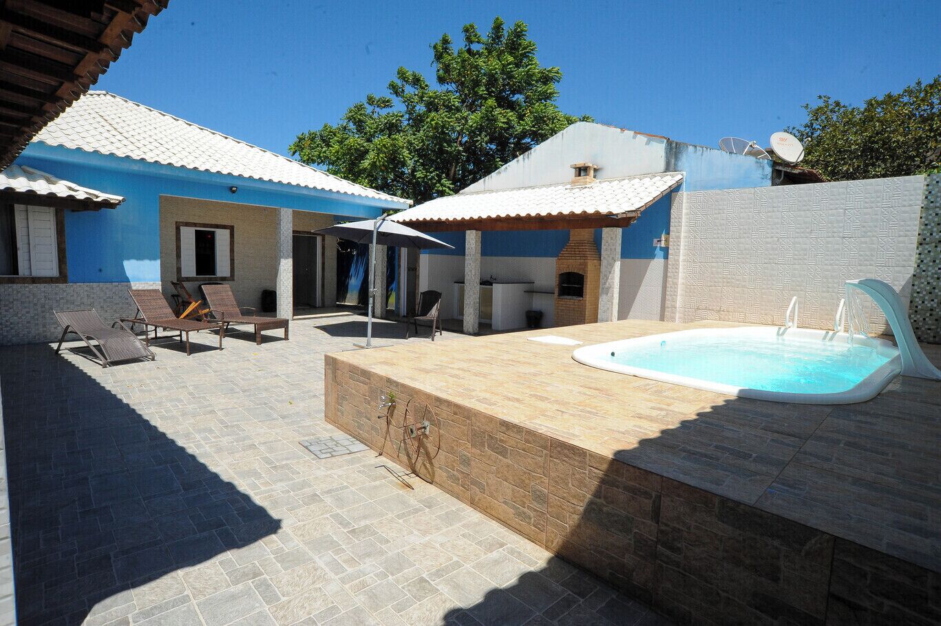 A pool area with lounge chairs, a hot tub, and a barbecue grill.