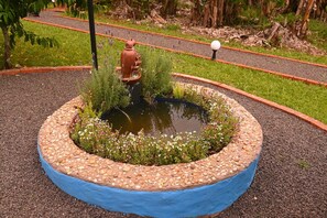 A circular garden with a pond, surrounded by a pebble border and a blue painted edge. - Horizonte Azul Cabin with Hot Tub and BBQ (Santa Rosa de Lima)