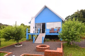 A blue house with a balcony, a staircase, and a brick fire pit. - Cabana Horizonte Azul com Hidro e Churrasqueira (Santa Rosa de Lima)