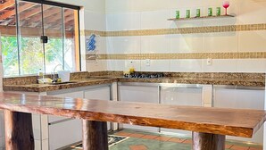 A spacious kitchen with a large wooden table, a gas stove, and hanging pendant lights.