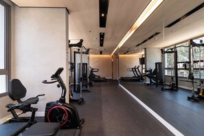 Ein modernes Fitnessstudio mit unterschiedlichen Trainingsgeräten, großen Fenstern und einem klaren, minimalistischen Design.