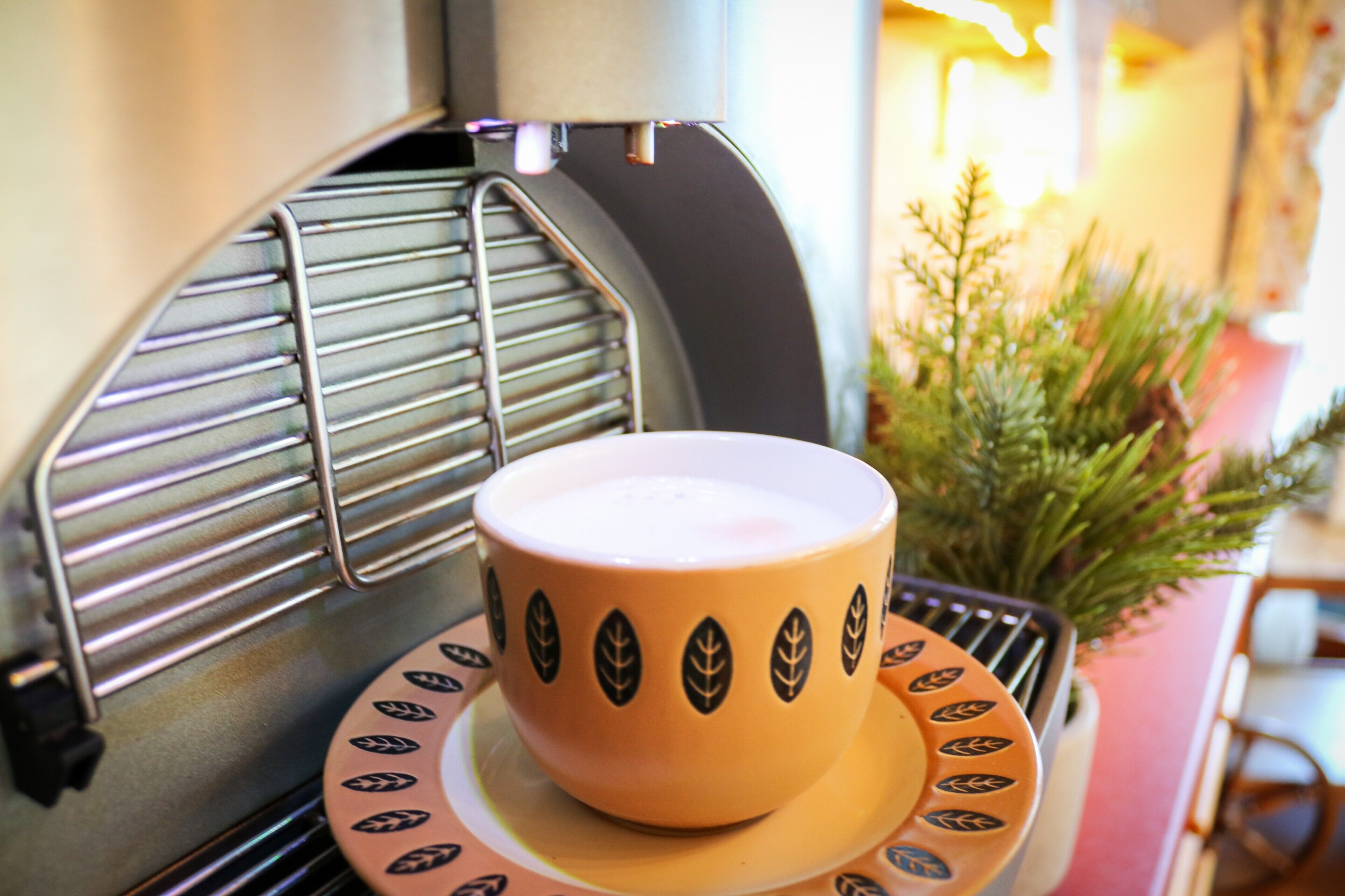 En kaffemaskine med kop og underkop på et fad.