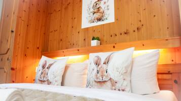 A wooden-paneled room with a bed featuring white bedding and pillows with rabbit prints.