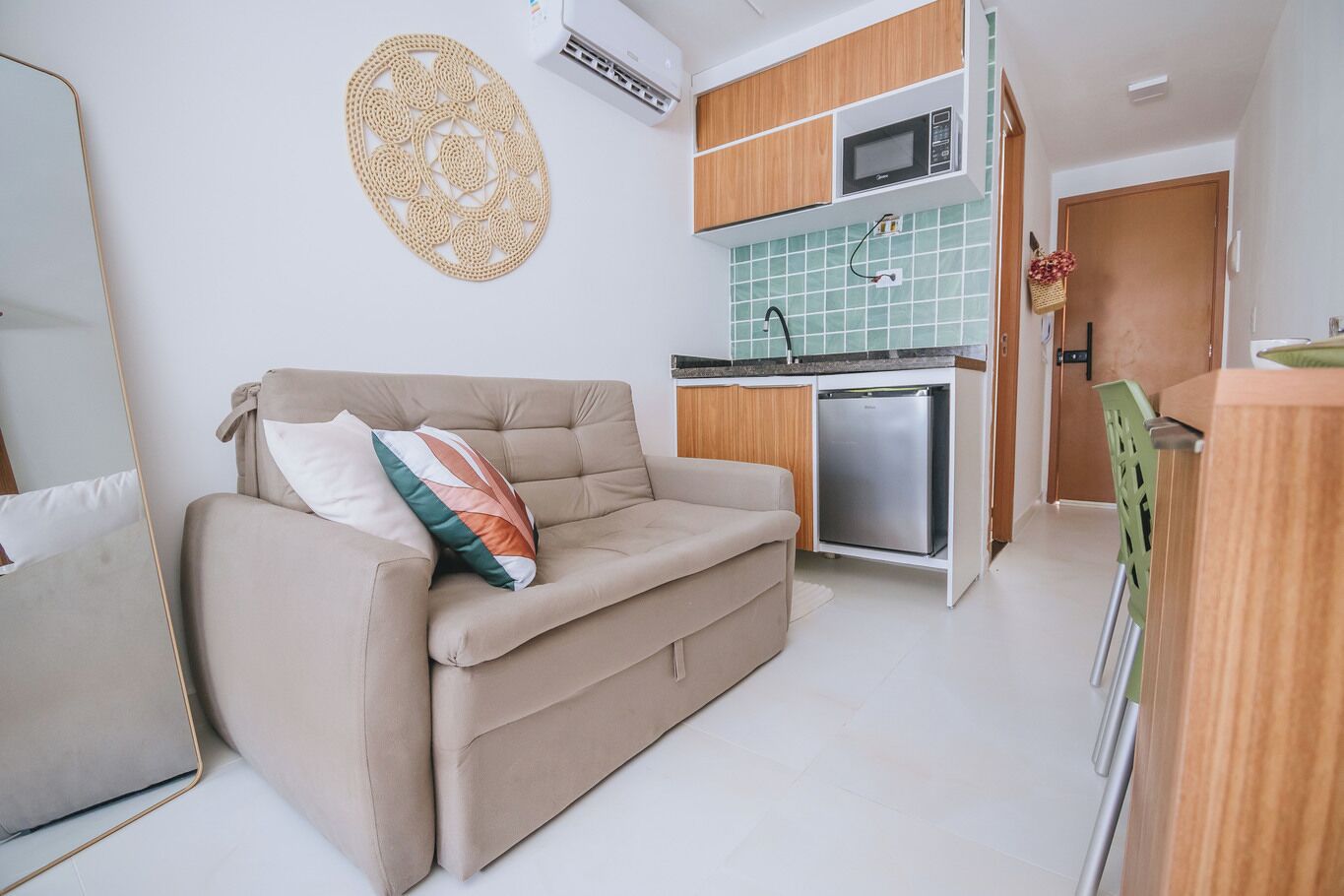 A compact living space with a sofa, kitchenette, and a small refrigerator.