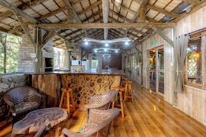 A rustic interior with a wooden bar, wicker furniture, and a stone wall.