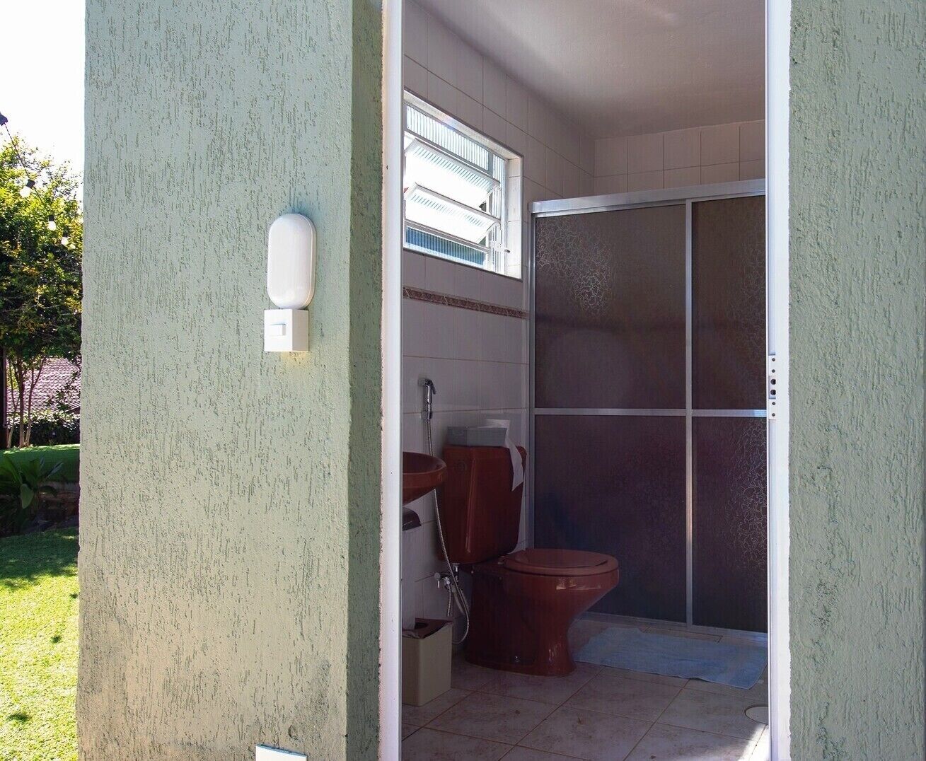 A bathroom with a toilet, a shower, and a window.