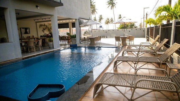 Une piscine entourée d’une terrasse carrelée, agrémentée de chaises longues et de parasols.