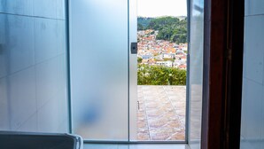 A bathroom with a large window, a red mat, and a view of a cityscape. - Casa com lareira, Wi-Fi e varanda com vista (Campos do Jordão)