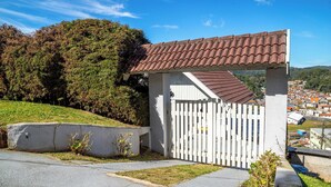 A gated property with a tiled roof and a white fence. - Casa com lareira, Wi-Fi e varanda com vista (Campos do Jordão)