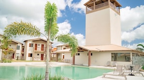 A resort with a swimming pool, multiple buildings with balconies, and a tower structure. - Dunas de Amaro Chalet: 3 Suites, Pool & Viewpoint (Santo Amaro)