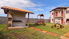A residential area with a patio, a small play structure, and a two-story building with a balcony.