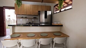 A compact kitchen with a built-in refrigerator, wooden cabinets, and a dining area with four chairs and a table.