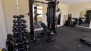 A gym with various exercise equipment, including a squat rack, dumbbells, and a bench.