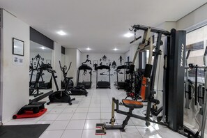 A gym with various exercise equipment, including treadmills, ellipticals, and weight machines.