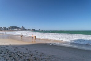 A beach with people walking along the shore, a sandy beach, and a clear blue sky. - Studio 45 m from Copacabana beach: AC and Wi-Fi (Rio de Janeiro)