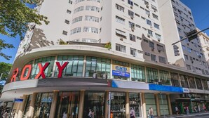 A multi-story building with a large glass facade and the word "ROXY" prominently displayed on the ground floor. - Studio com Wi-Fi e Ar a 45m da Praia de Copacabana (Rio de Janeiro)