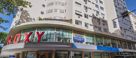 Un edificio de varios pisos con un llamativo letrero que dice 'ROXY' en la planta baja.