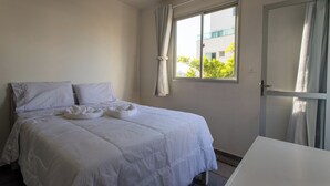 Een hotelkamer met een bed, een raam met gordijnen en een deur.