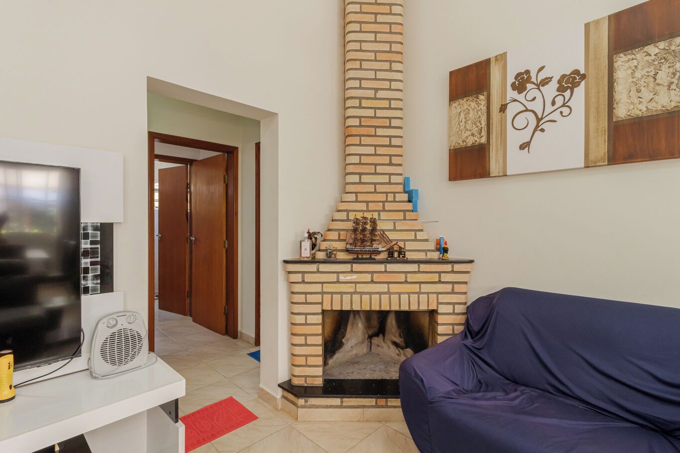 A living room with a brick fireplace, a television, and a sofa.
