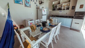 Un comedor con una mesa de vidrio, sillas blancas y una hamaca azul.
