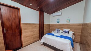Una habitación de hotel con una puerta de madera, una cama con una manta azul y una pared blanca con un cartel.