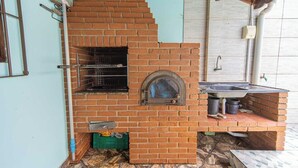 A brick-built outdoor oven with a window, a sink, and a tiled floor. - Casa com Piscina e Garagem a 550m da Praia (Peruíbe)