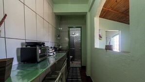 Een smalle keuken met een groen aanrecht, een broodrooster en een magnetron. Een raam met uitzicht is zichtbaar.