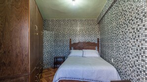 Een slaapkamer met een houten bed, een kledingkast en een betegelde muur.
