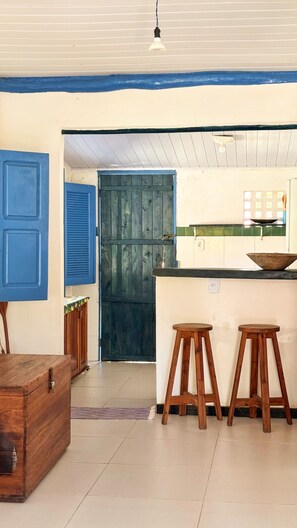 A kitchen with a blue door, wooden stools, and a wooden chest. - Casa Moreira: Veranda & Beach 200m Away | Corumbau (Prado)